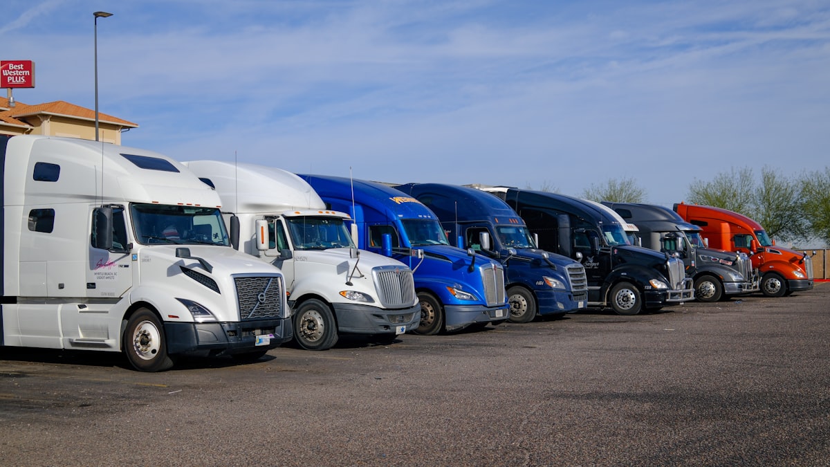 Row of modern semi trucks parked professionally at a commercial fleet yard