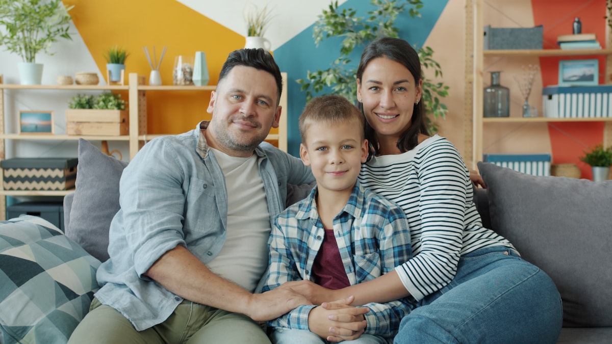 Family of three sitting together on a couch at home